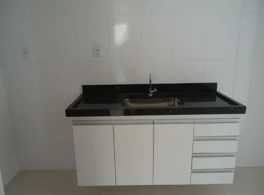 Cozinha com bancada de granito preto e armários brancos
