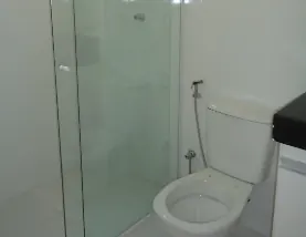 Banheiro com revestimento branco e box de vidro